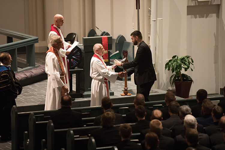 Director of Placement Dr. Wallace Becker, center, hands Dustin Atkinson his call papers showing his placement at Star of the North Lutheran Church in Kenai, Alaska.